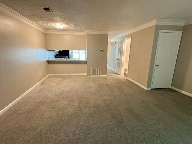 a view of an empty room and a kitchen