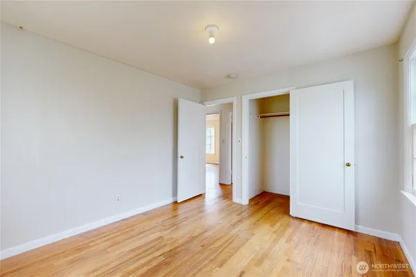 a view of an empty room with wooden floor and closet