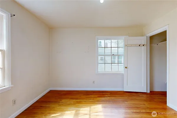 a view of empty room with wooden floor and fan