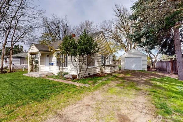 a view of a house with a yard and large tree