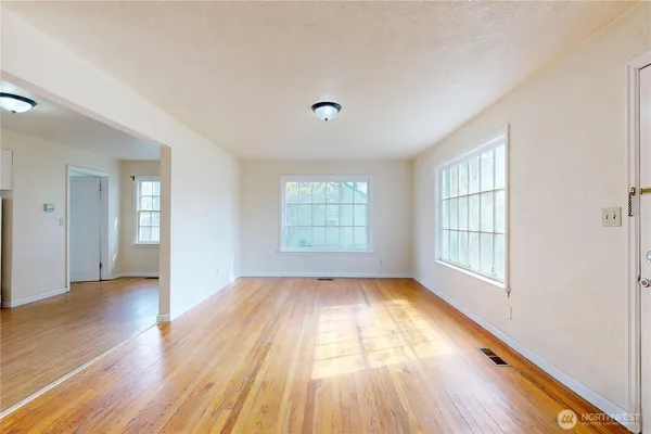 an empty room with wooden floor and windows