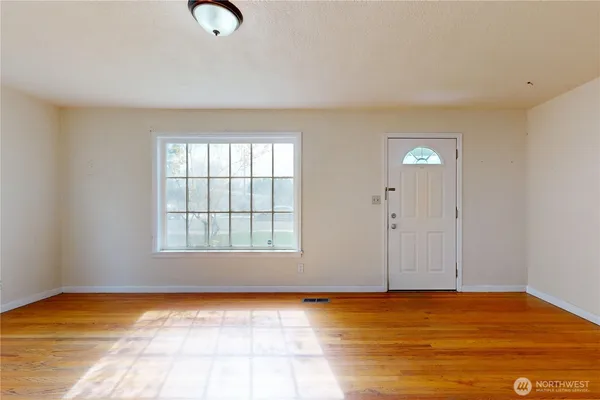 a view of an empty room with window and wooden floor