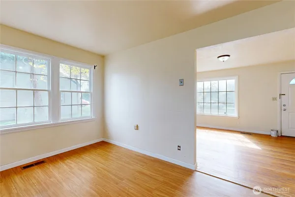 an empty room with wooden floor and windows