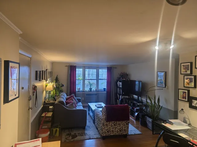 a living room with furniture a bookshelf and a flat screen tv