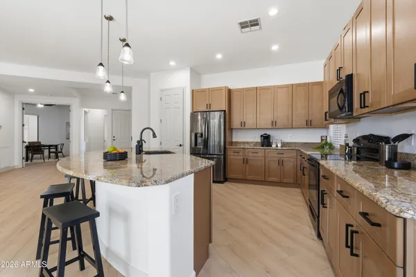 a kitchen with stainless steel appliances granite countertop a table chairs refrigerator and microwave