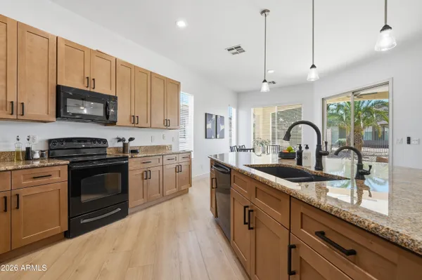 a kitchen with stainless steel appliances granite countertop a sink a stove and a wooden floors