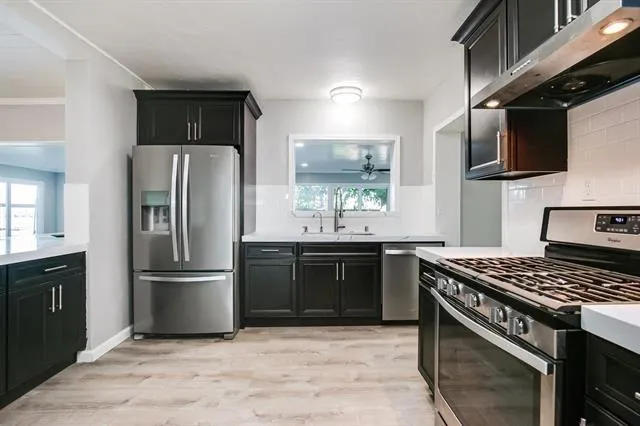 a kitchen with stainless steel appliances granite countertop a stove a refrigerator and a sink