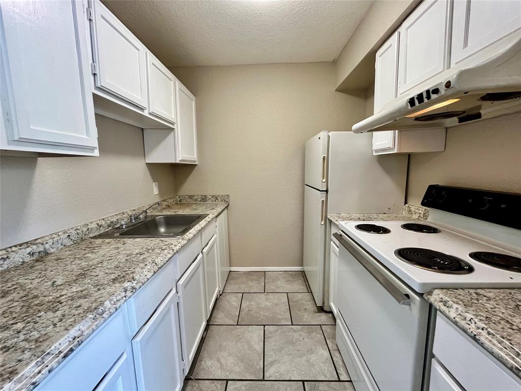 701 West Sycamore Street, Unit 104 Denton, TX 76201 - Photo 5 of 10 Upgraded kitchen featuring elegant granite-style countertops and a full suite of white appliances.