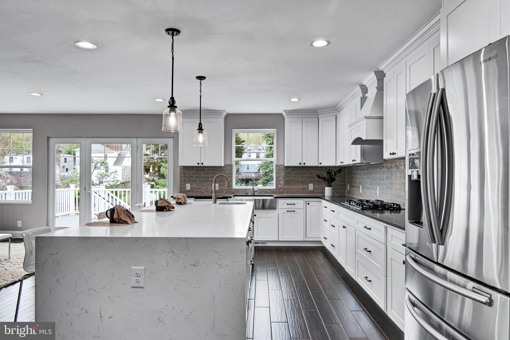 a kitchen with granite countertop a refrigerator a sink a center island and windows