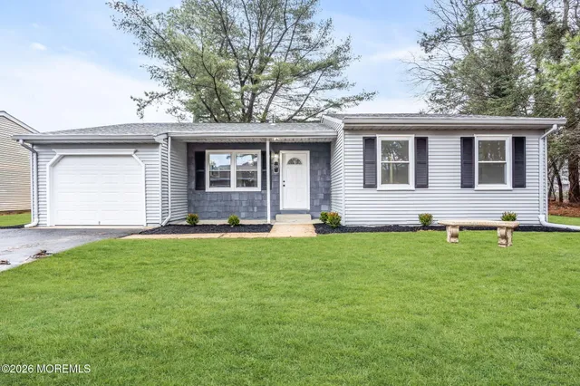 a front view of house with yard and trees in the background