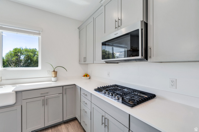 646 South Meade Street Mapleton, UT 84664 - Photo 4 of 46 Modern kitchen featuring light gray cabinetry, white countertops, a stainless steel over-the-range microwave, a built-in gas cooktop, and a farmhouse sink