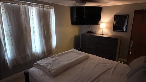 a bedroom with a bed tv and a window