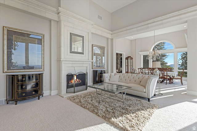 3222 Eagle View Circle Sandy, UT 84092 - Photo 8 of 60 Living area featuring carpet flooring, a high ceiling, a large fireplace, and a chandelier