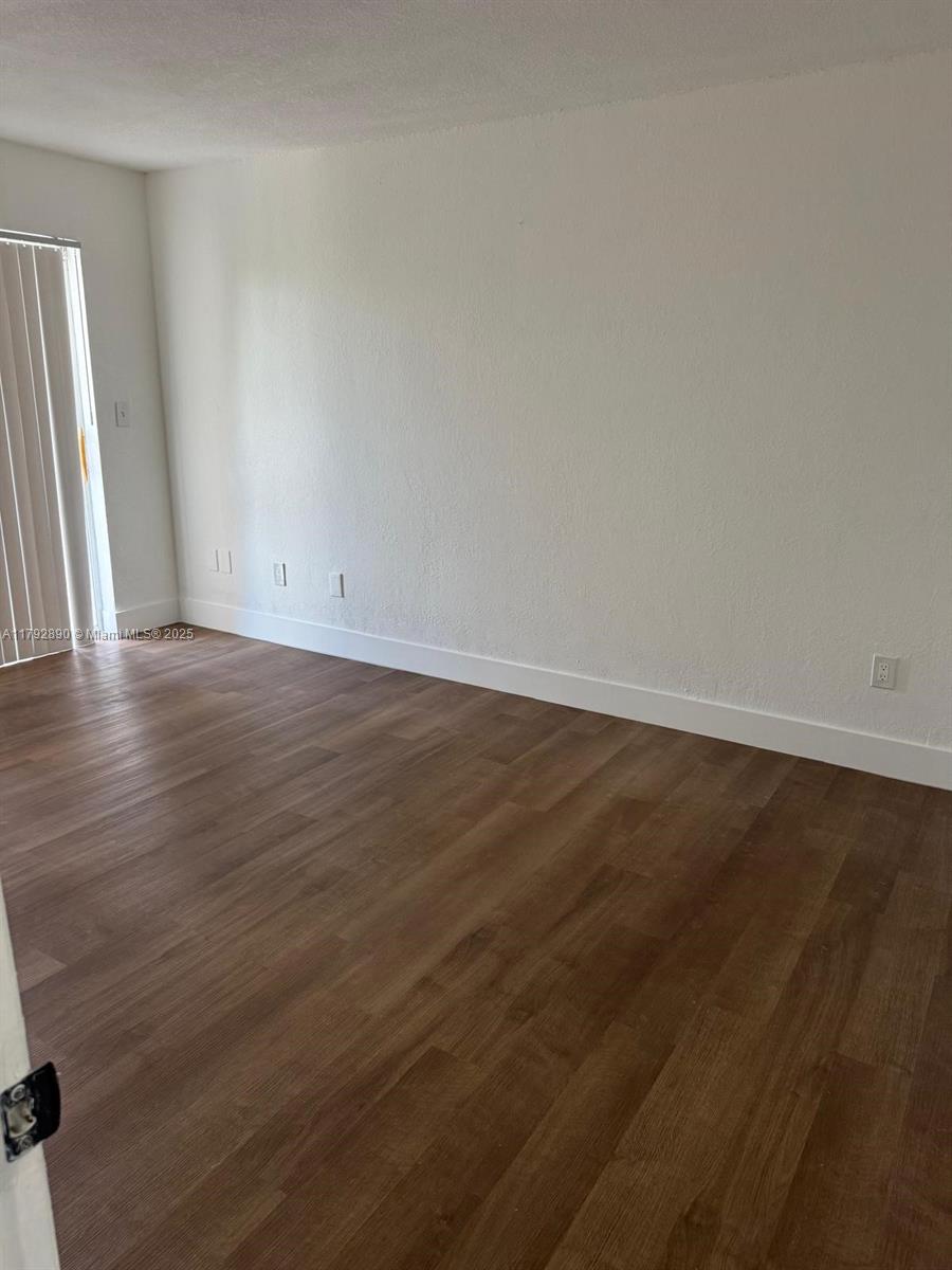 1350 West 53rd Street, Unit 33 Hialeah, FL 33012 - Photo 16 of 17 an empty room with wooden floor and windows