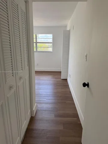 a view of a hallway with wooden floor and closet