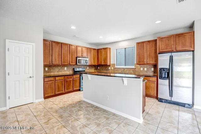 a kitchen with granite countertop a refrigerator and a stove top oven