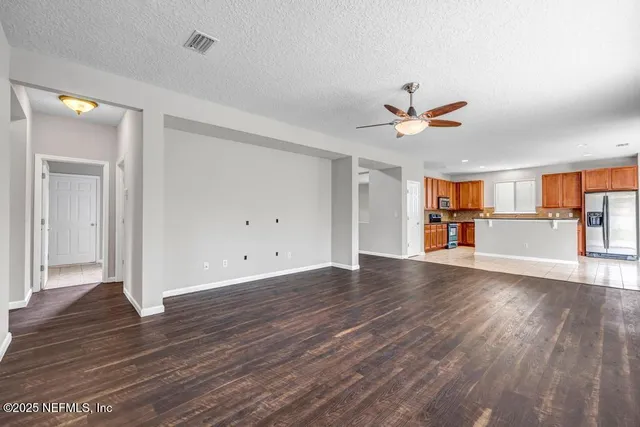 wooden floor in an empty room with a window and a kitchen