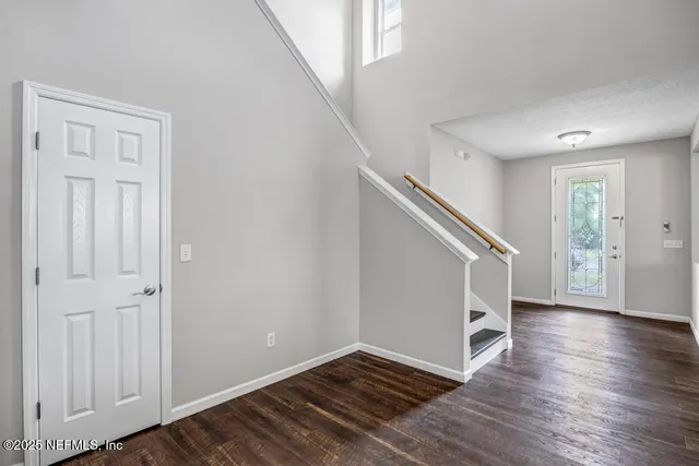 a view of an empty room with wooden floor and stairs