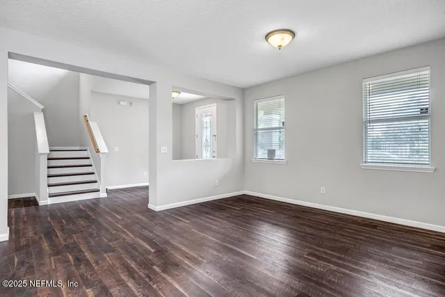 a view of an empty room with wooden floor and window