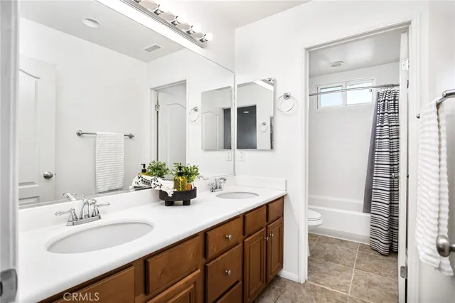 a bathroom with double vanity sinks a large mirror and a window