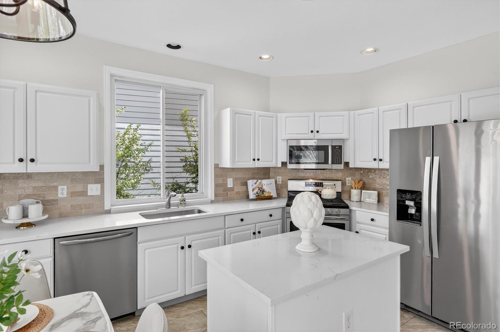 2445 East Lansdowne Court Highlands Ranch, CO 80126 - Photo 16 of 49 a kitchen with stainless steel appliances granite countertop a sink a stove a refrigerator cabinets and a window