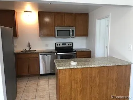 a kitchen with stainless steel appliances granite countertop a sink a stove a microwave and a refrigerator