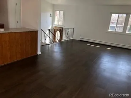 an empty room with wooden floor cabinet and windows