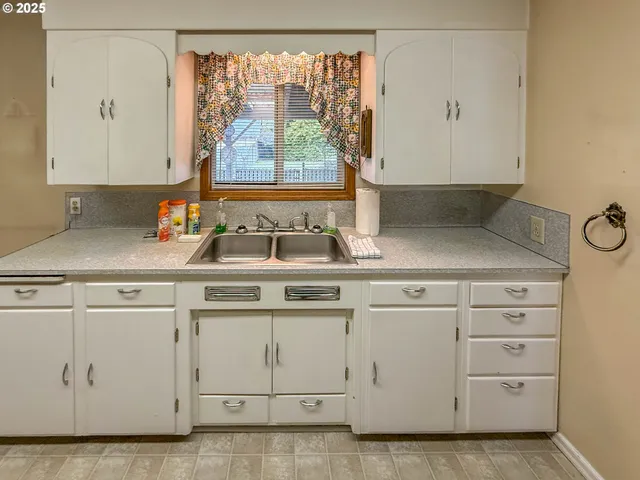 a kitchen with white cabinets and a window