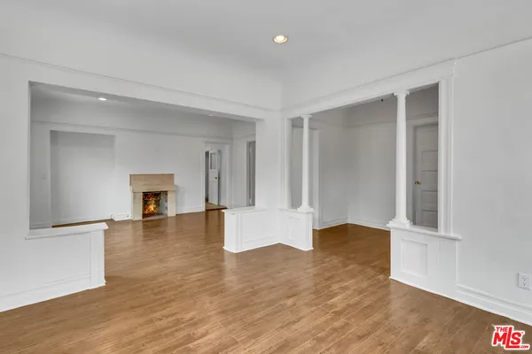 a view of an empty room with window and wooden floor