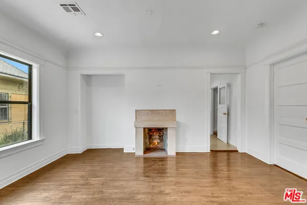 a view of an empty room with wooden floor and a window