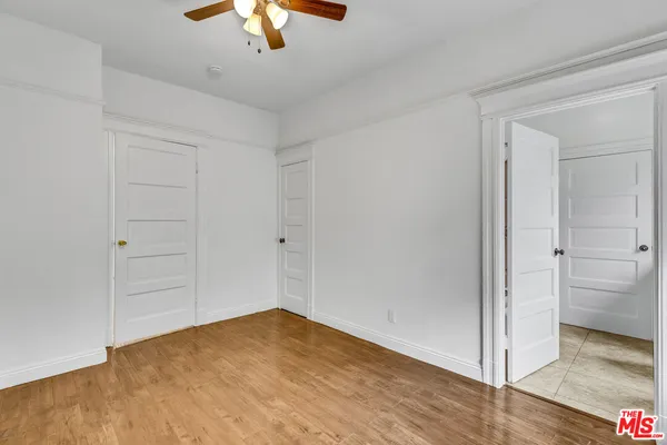 a view of empty room with wooden floor and ceiling fan