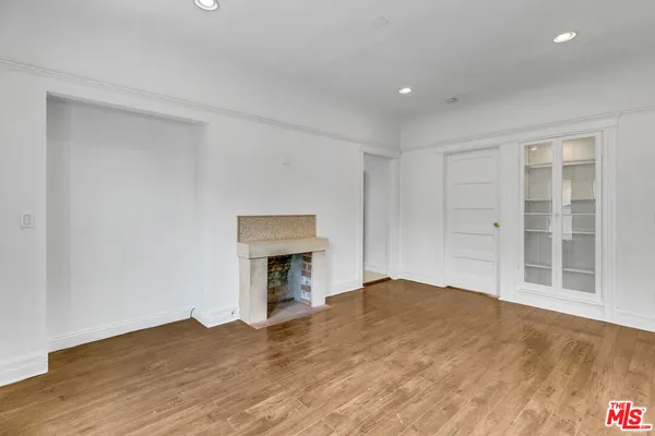 a view of empty room with wooden floor and fireplace