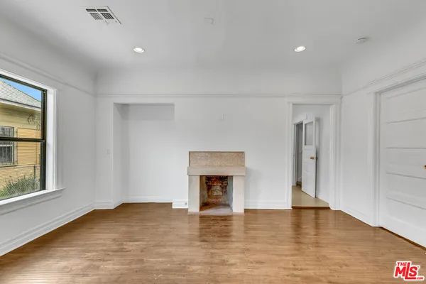 a view of empty room with wooden floor and fireplace
