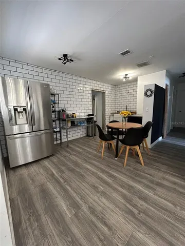 a kitchen with stainless steel appliances kitchen island granite countertop a table chairs and a refrigerator