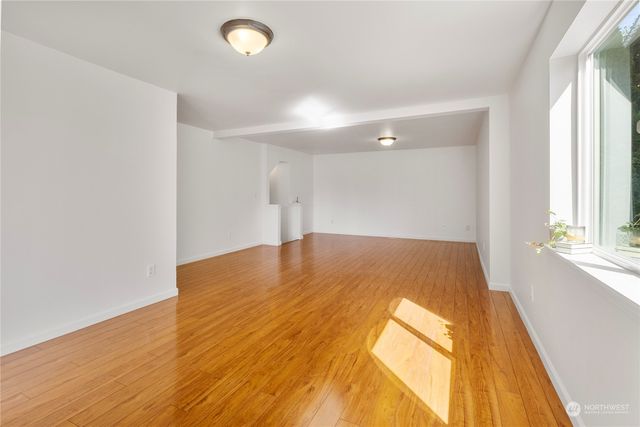 a view of empty room with wooden floor and fan