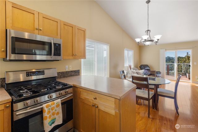 a kitchen with stainless steel appliances granite countertop a stove a sink dishwasher a dining table and chairs with wooden floor