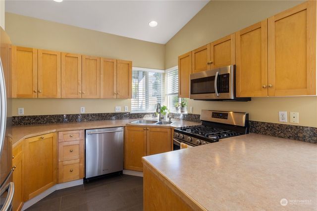 a kitchen with stainless steel appliances granite countertop a stove a sink and a microwave