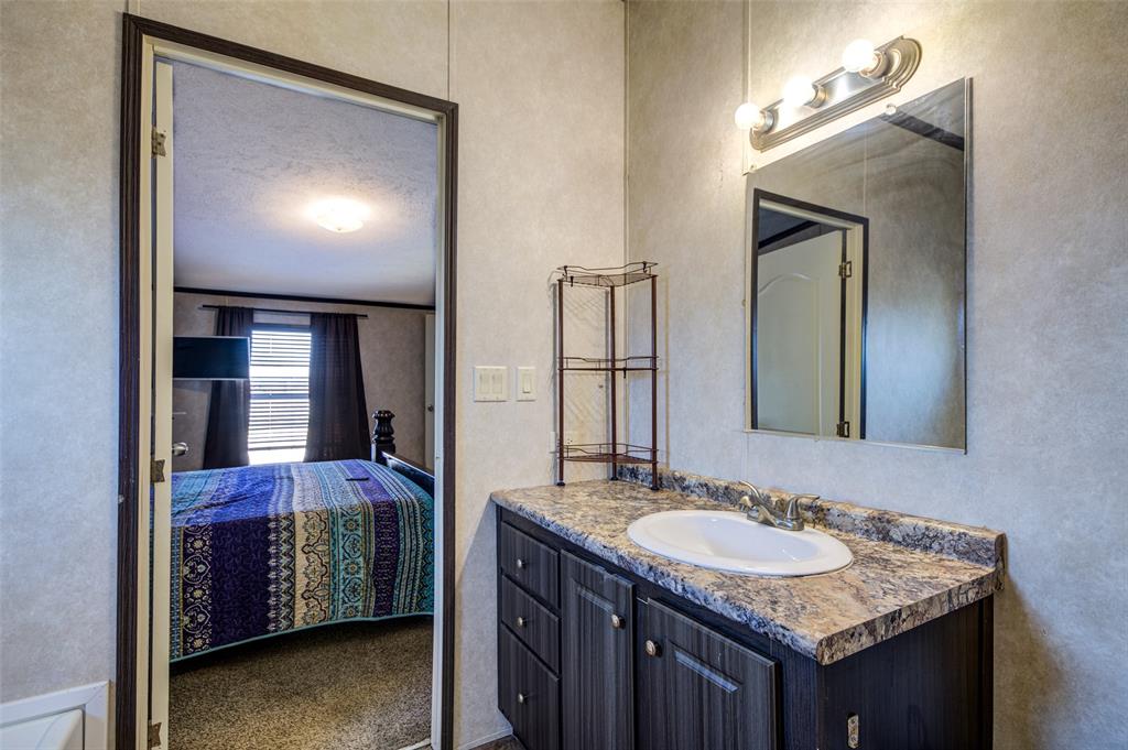 1420 County Road 4522 Decatur, TX 76234 - Photo 22 of 24 a bathroom with a granite countertop sink and a mirror