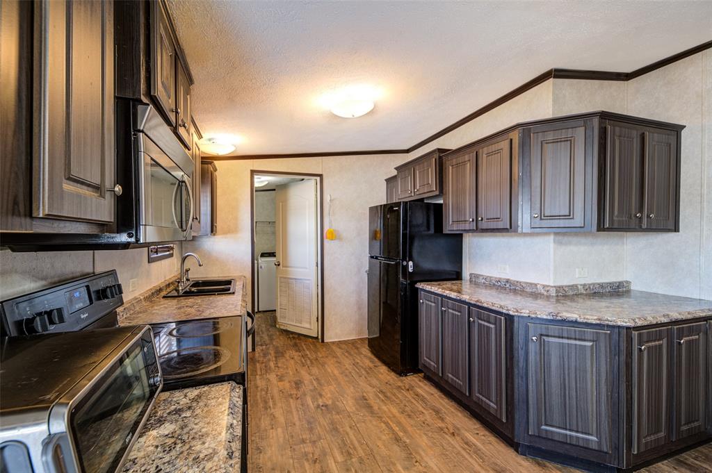 1420 County Road 4522 Decatur, TX 76234 - Photo 9 of 24 a kitchen with stainless steel appliances granite countertop a refrigerator a stove and a sink with wooden cabinets