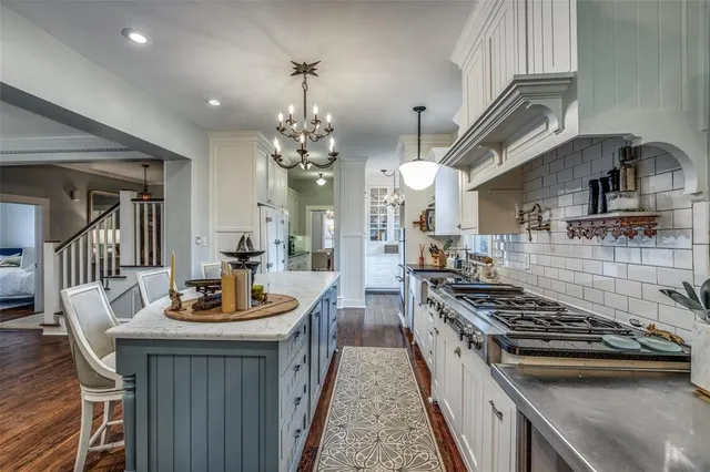 a kitchen with stainless steel appliances a stove a sink dishwasher a dining table and chairs with wooden floor