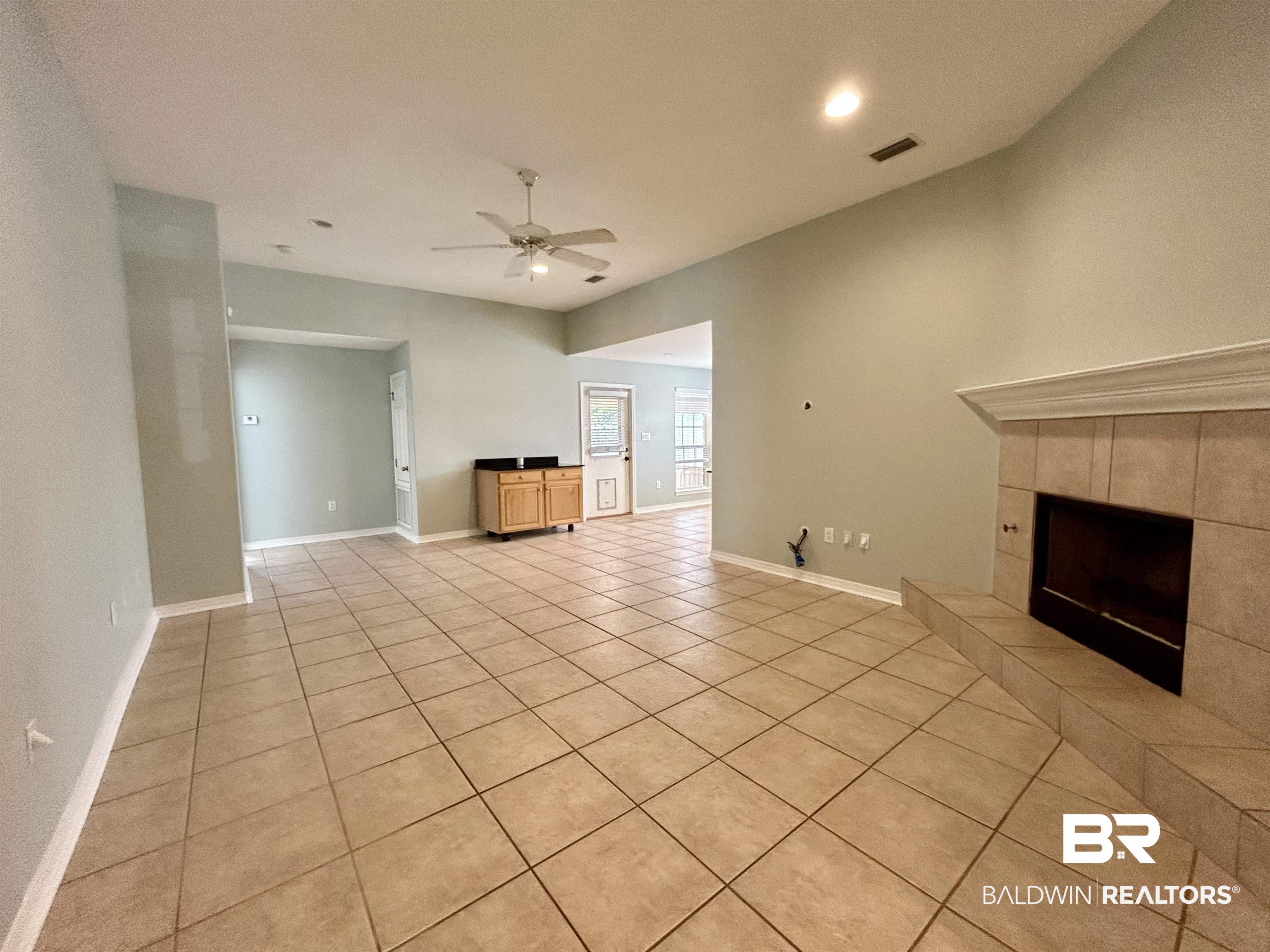 7198 Raintree Lane Gulf Shores, AL 36542 - Photo 7 of 33 Spacious room featuring tile flooring, a corner fireplace with a tile surround and mantel, and a built-in cabinet with a dark countertop