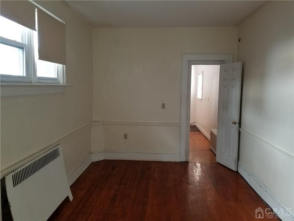110 Rector Street Perth Amboy, NJ 08861 - Photo 8 of 15 an empty room with wooden floor and windows