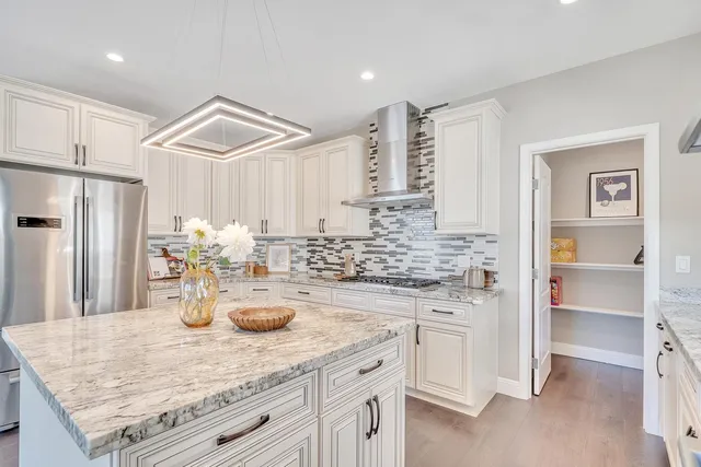a kitchen with kitchen island granite countertop a white cabinets and refrigerator