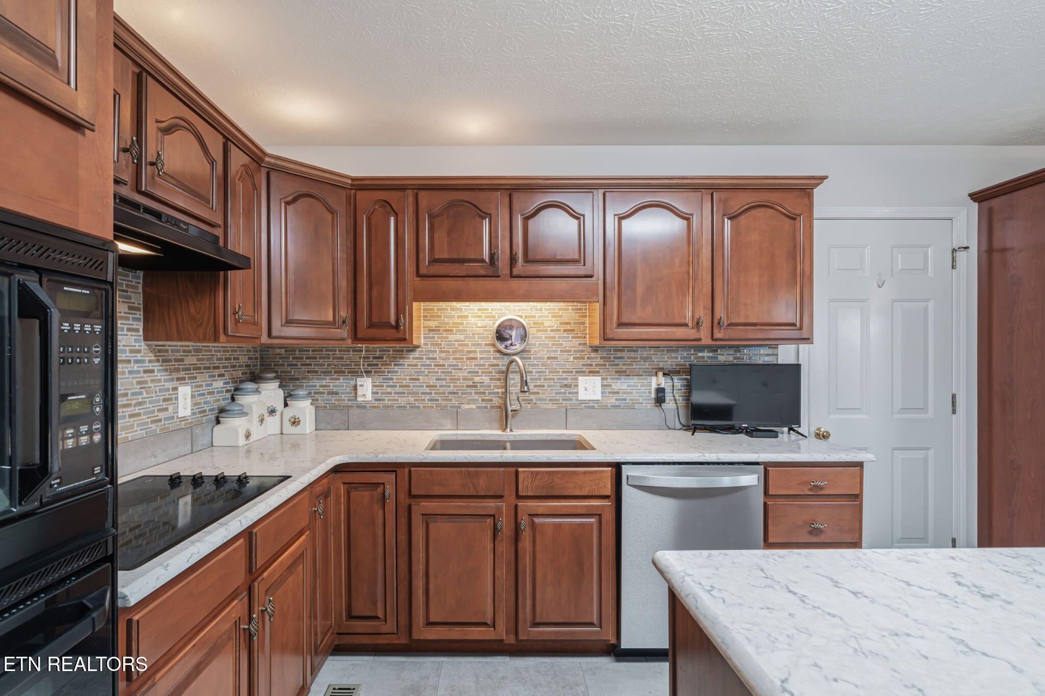 7030 Westerly Winds Road Knoxville, TN 37931 - Photo 17 of 40 a kitchen with stainless steel appliances granite countertop a sink dishwasher stove and refrigerator with wooden cabinets