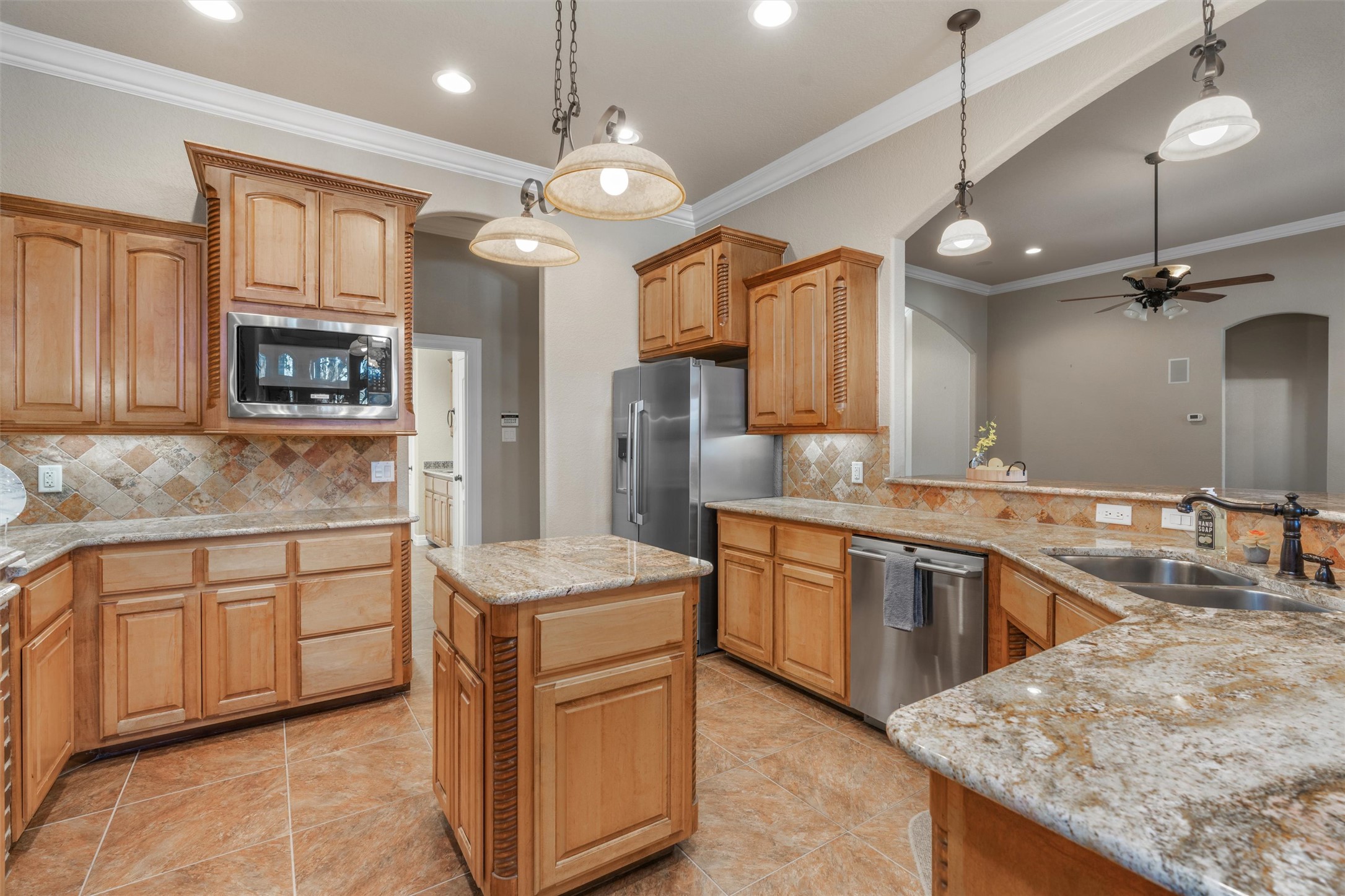 8006 Ridgeway Court Nolanville, TX 76559 - Photo 18 of 40 Kitchen featuring a center island, light stone counters, crown molding, ceiling fan, and stainless steel appliances