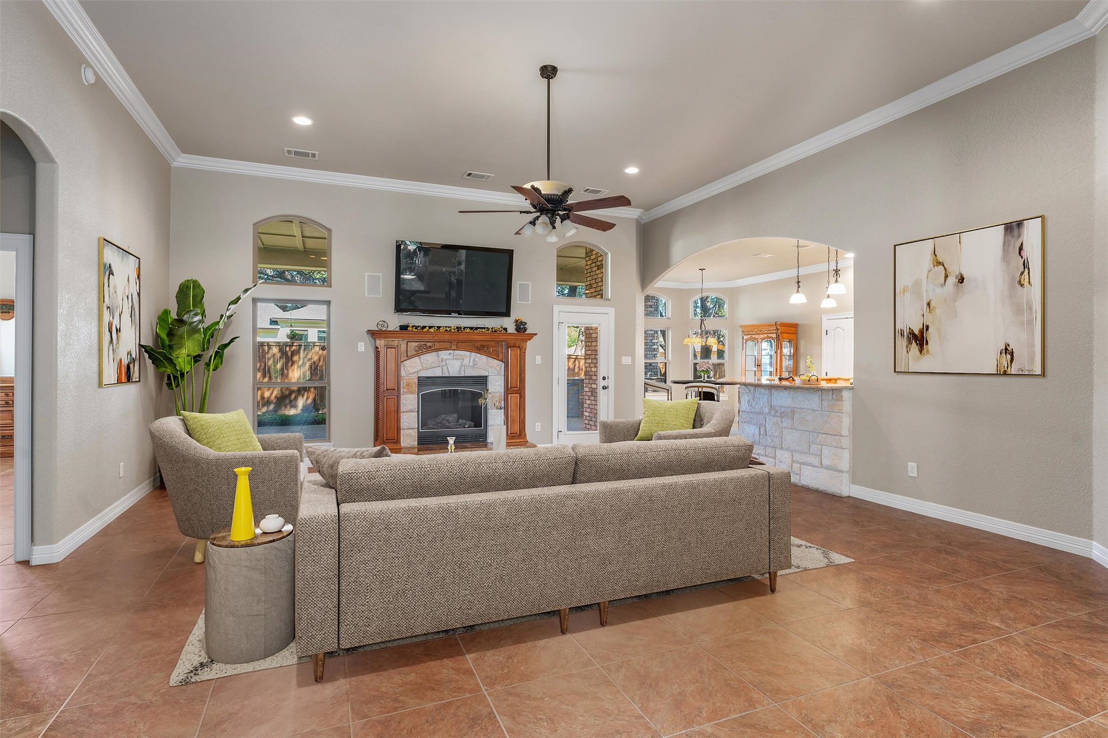 8006 Ridgeway Court Nolanville, TX 76559 - Photo 9 of 40 Living area featuring arched walkways, crown molding, ceiling fan, a stone fireplace, and recessed lighting. Virtually staged.