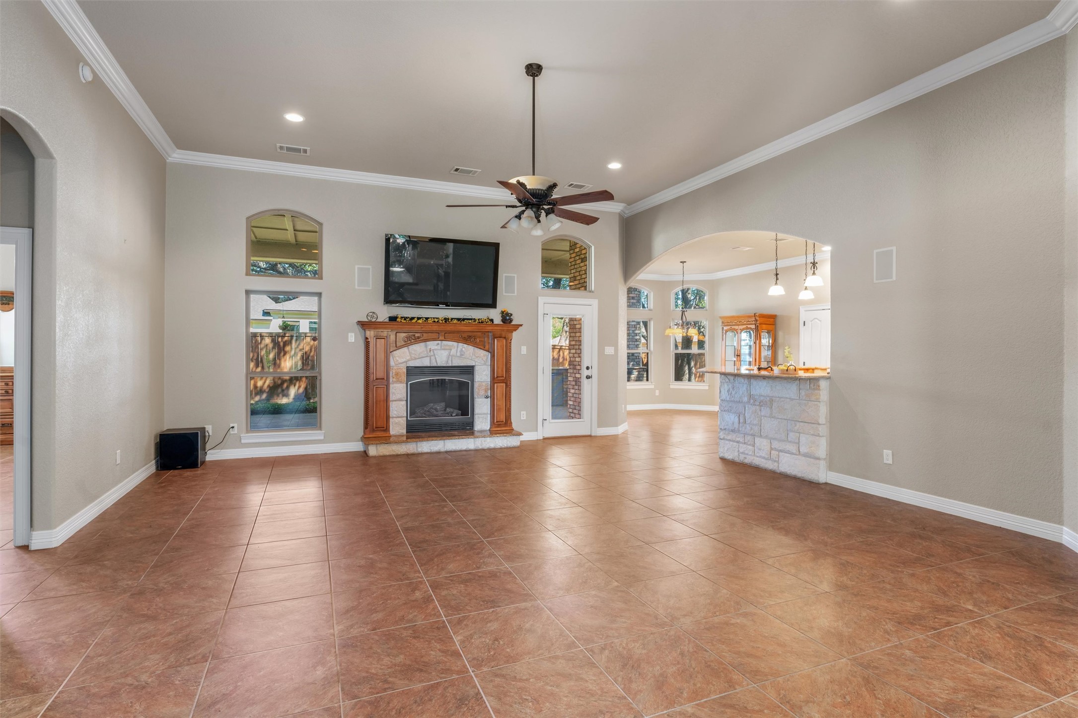 8006 Ridgeway Court Nolanville, TX 76559 - Photo 10 of 40 Unfurnished living room featuring arched walkways, ornamental molding, a ceiling fan, a stone fireplace, and recessed lighting