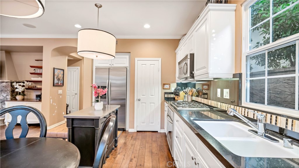 55 Bower Tree Irvine, CA 92603 - Photo 23 of 29 a large kitchen with stainless steel appliances granite countertop a sink dishwasher a stove a dining table and chairs with wooden floor