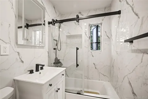 a bathroom with a sink vanity granite tub shower and mirror