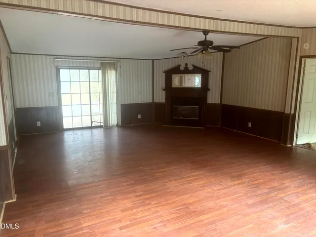 a view of empty room with wooden floor and furniture
